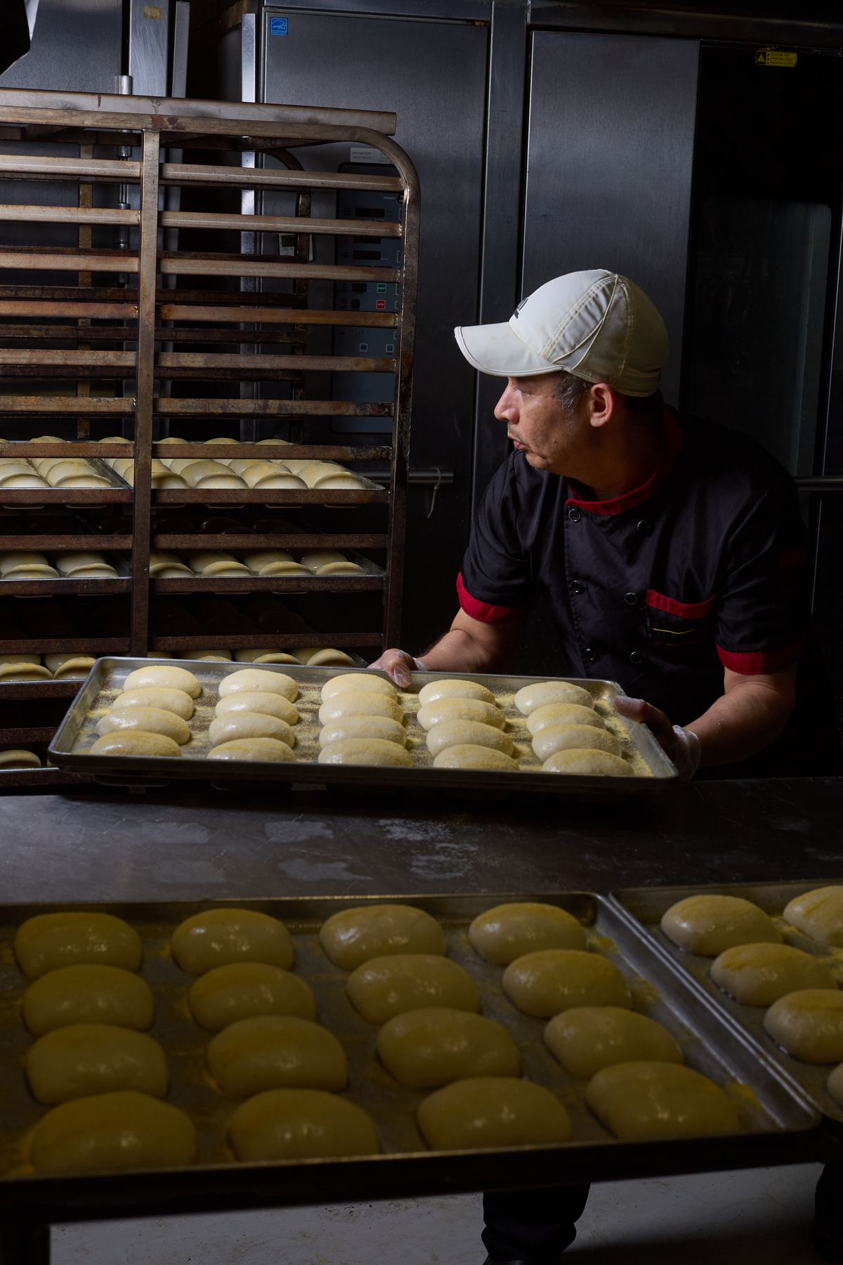 Chef carrying a tray of proofed buns