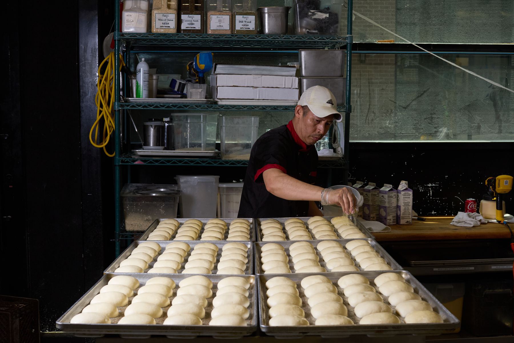 Baker seasoning trays of proofed dough in the bakery