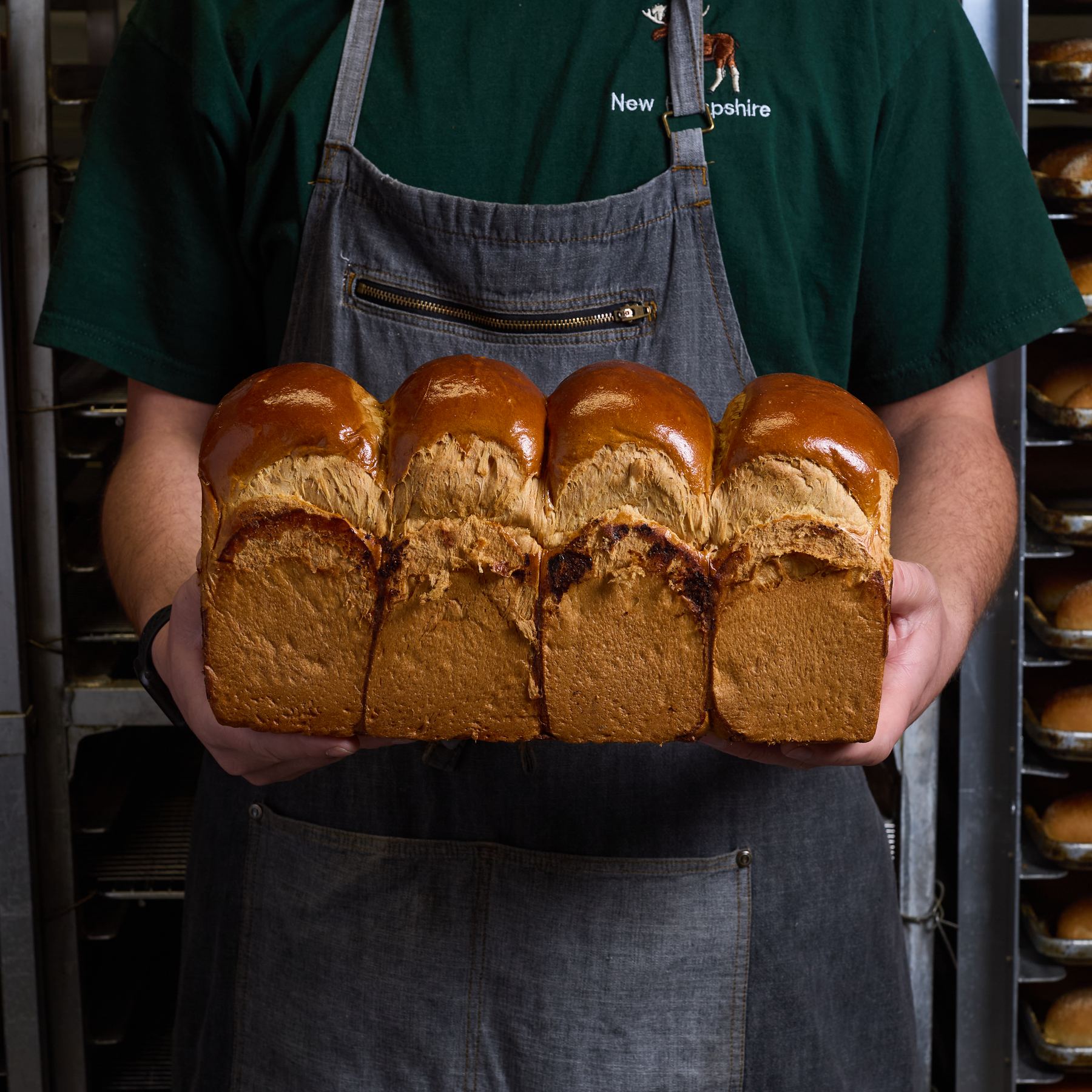 Baker holding a fresh peaked milk bread loaf